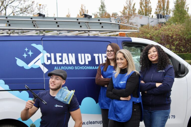 Schoonmaakteam van vier medewerkers staat geposeerd voor schoonmaakbus